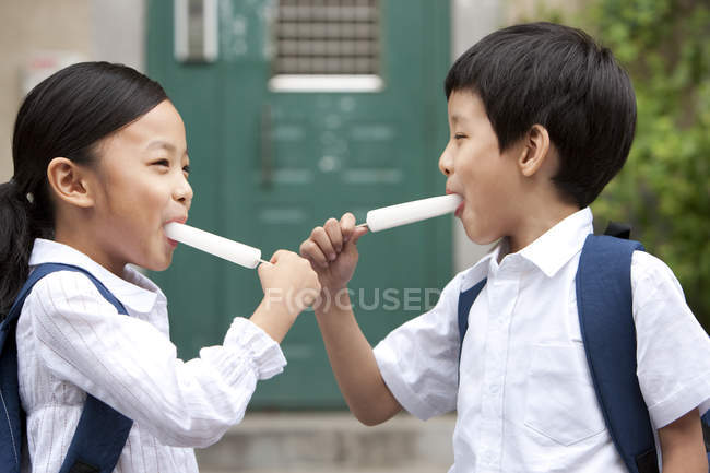 Chinese children eating ice pops on street — Stock Photo