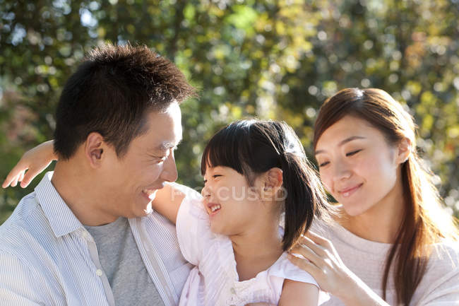 Felice genitori cinesi che trasportano figlia nel parco — Foto stock