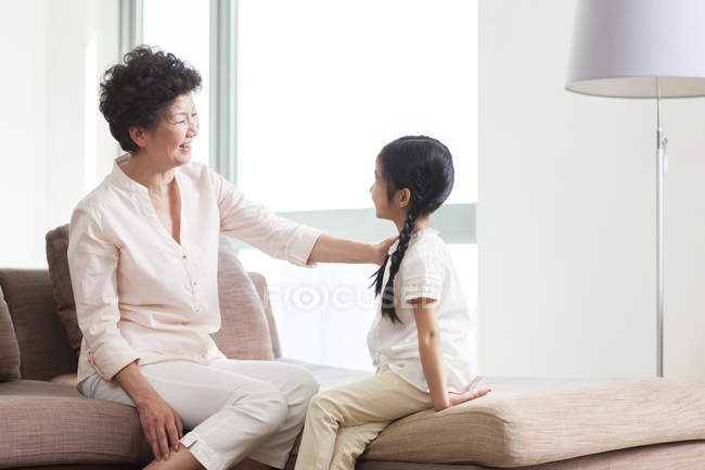 Chinês avó e neta falando no sofá — Fotografia de Stock