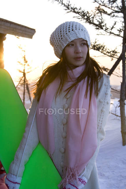 Chinese woman holding green snowboard — Stock Photo