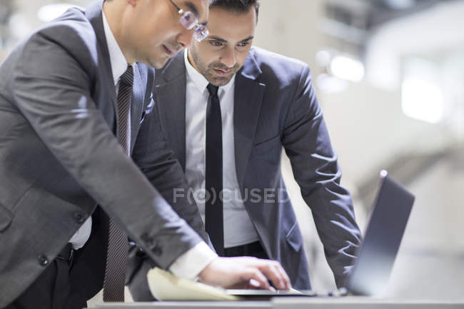 Businessmen using laptop at industrial factory — Stock Photo