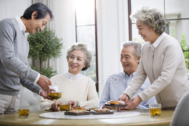 Старшие китайские друзья расслабляются и разговаривают во время чаепития — стоковое фото