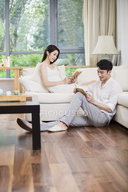 Jovem casal chinês ler livros na sala de estar — Fotografia de Stock