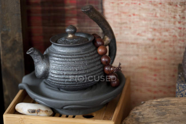 Китайский чайник и молитвенные бусы на деревянном подносе, крупным планом — стоковое фото