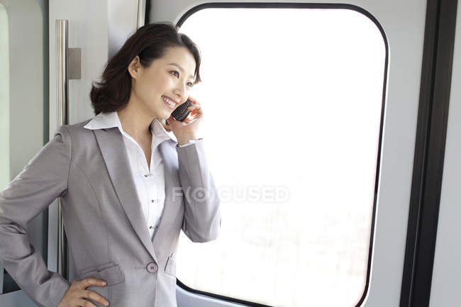 Chinese businesswoman talking on phone in subway train — Stock Photo