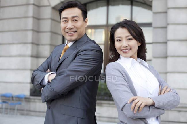Confident Chinese business people standing back to back in financial district — Stock Photo