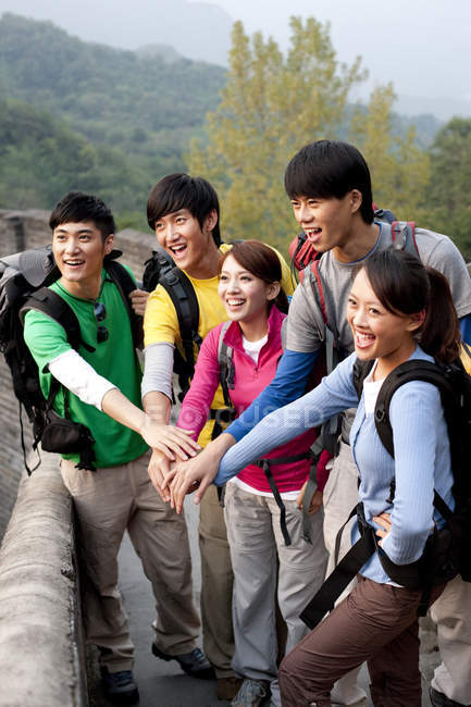 Excursionistas chinos apilándose las manos y posando en la Gran Muralla - foto de stock