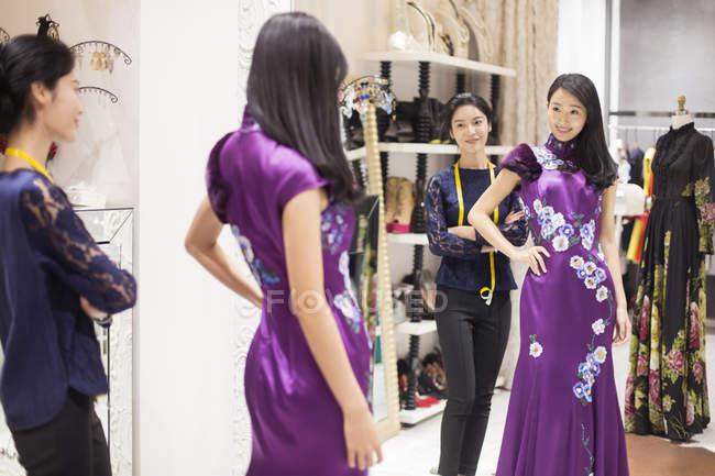 Diseñador de moda chino examinando vestido en el cliente - foto de stock