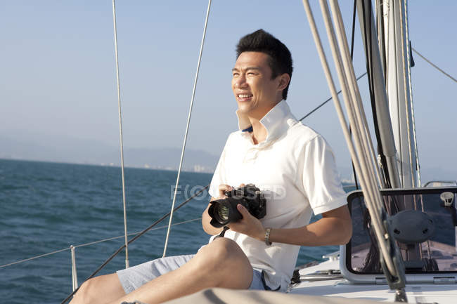 Chinese man holding digital camera on boat deck — Stock Photo