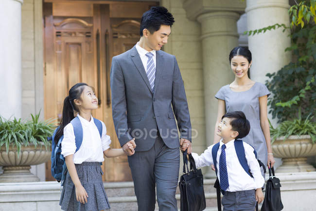 Chino negocio pareja con niños caminando de la mano en la calle - foto de stock