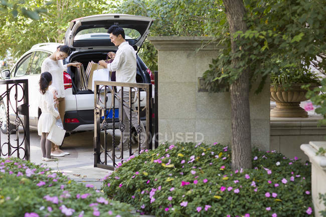 Familia china sacando bolsas de la cajuela del coche - foto de stock