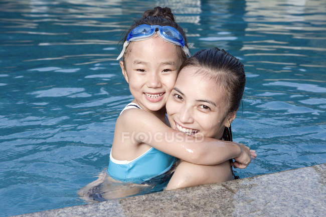 Chinese mother hugging daughter at swimming pool — Stock Photo