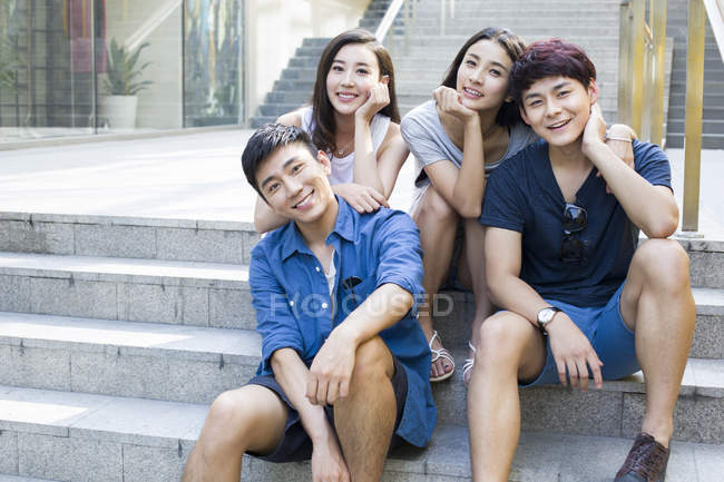 Amici cinesi sulle scale e guardando in macchina fotografica — Foto stock