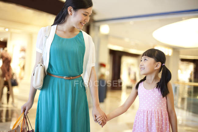 Китайський мати і дочка, тримаючись за руки при здійсненні покупок в універмазі — стокове фото