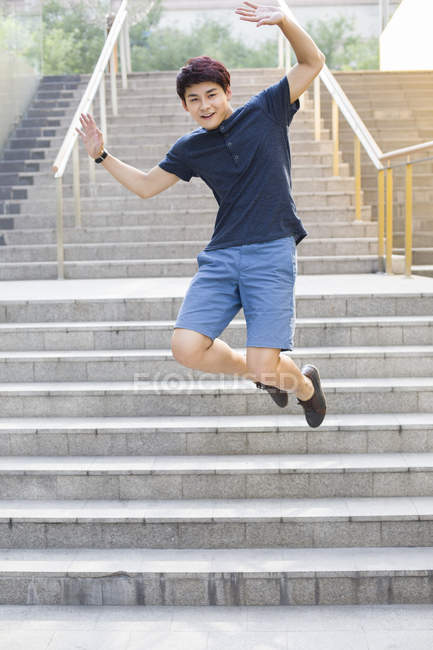 Chinese young man jumping down steps — Stock Photo