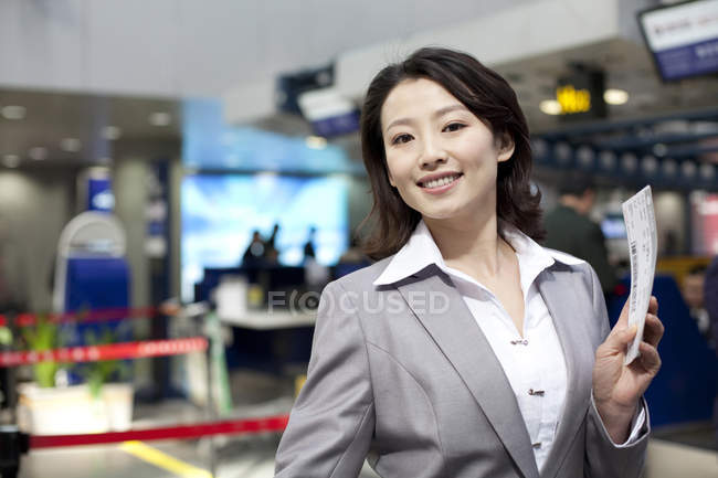 Chinesische Geschäftsfrau hält Ticket im Flughafen — Stockfoto