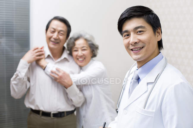 Médico chinês com abraço casal sênior no hospital — Fotografia de Stock