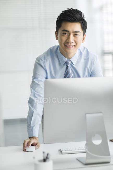 Китайский бизнесмен стоит за компьютером в офисе — стоковое фото
