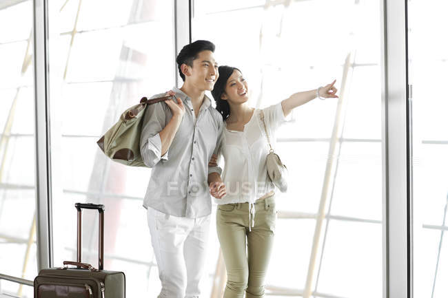 Китайская пара стоит в аэропорту и смотрит на вид — стоковое фото