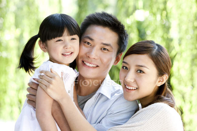 Happy Chinese parents carrying daughter in park — Stock Photo