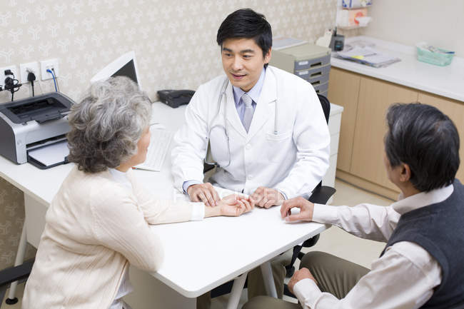 Chinese doctor taking pulse of senior woman in hospital — Stock Photo