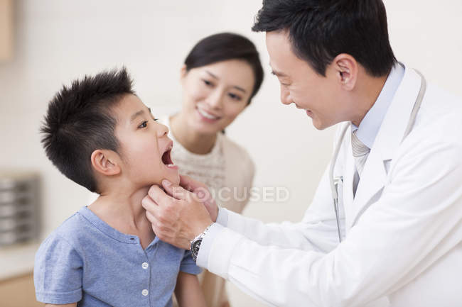 Médico chino examinando boca chico - foto de stock