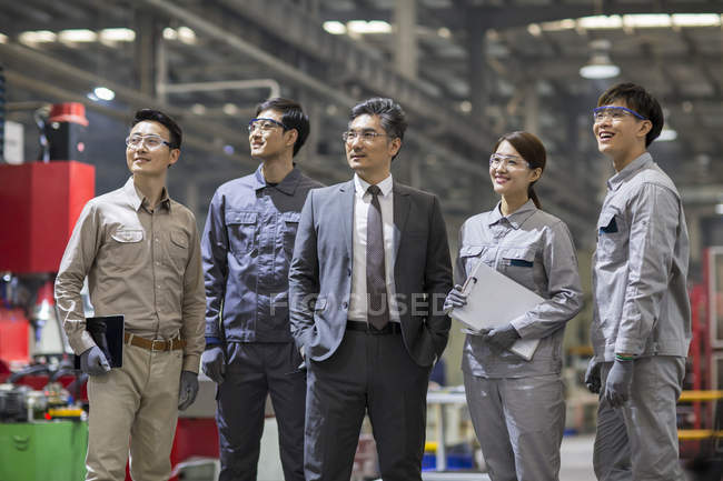 Maduro chinês empresário e engenharia equipe posando no fábrica — Fotografia de Stock