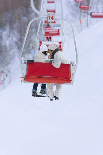 Casal chinês usando elevador de esqui no resort de inverno — Fotografia de Stock