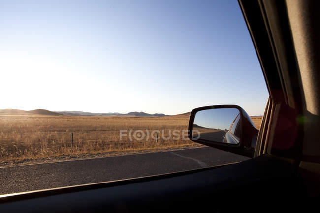 Auto Seitenspiegel mit Straße durch Feld in China — Stockfoto