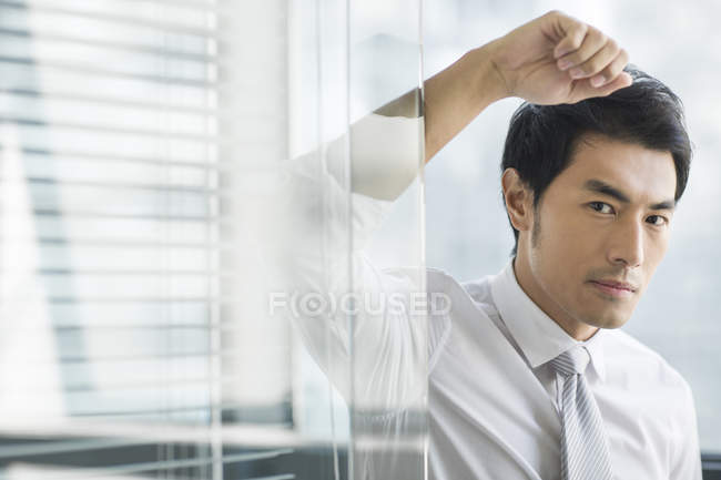 Portrait of Chinese businessman leaning on door — Stock Photo