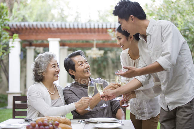 Happy Chinese family celebrating with champagne outdoors — Stock Photo