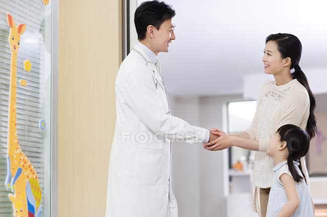 Chinese girl mother holding doctor hands in hospital — Stock Photo