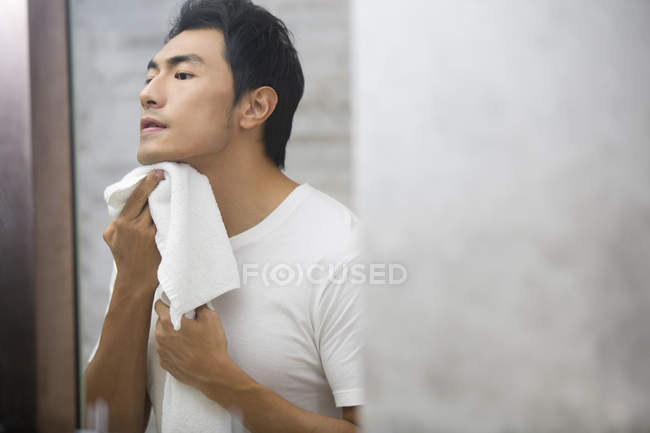 Chinese man rubbing face with towel — Stock Photo