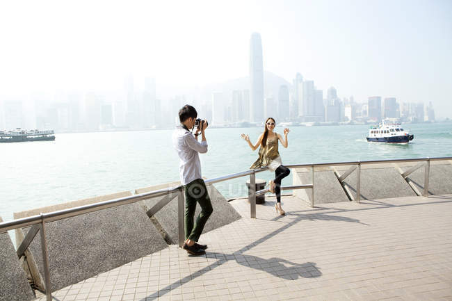 Homem chinês tirando foto de uma jovem mulher com câmera em Victoria Harbor, Hong Kong — Fotografia de Stock