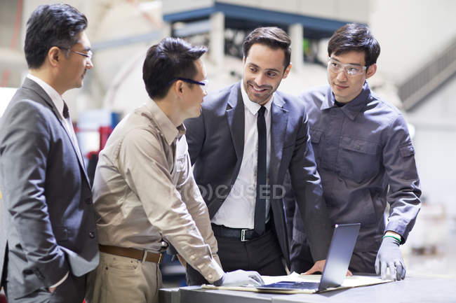 Uomini d'affari e ingegneri che si incontrano con il computer portatile in fabbrica — Foto stock