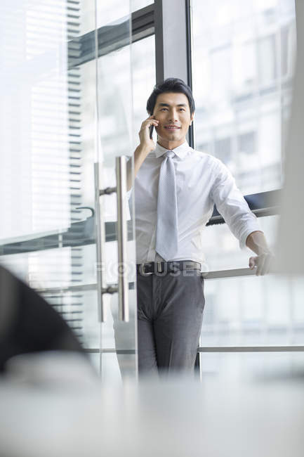 Китайский бизнесмен разговаривает по телефону в дверях офиса — стоковое фото