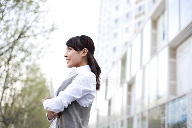 Вид сбоку на китайскую предпринимательницу, держащую цифровой планшет в городе — стоковое фото