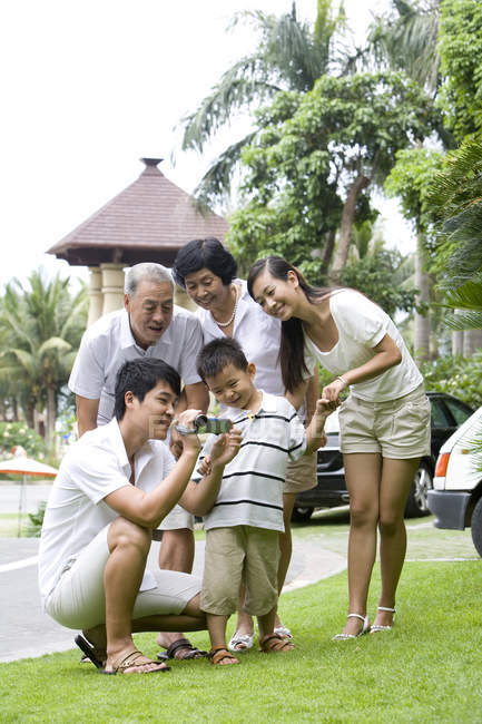 Chinese man filming with multi-generation family on vacation — Stock Photo