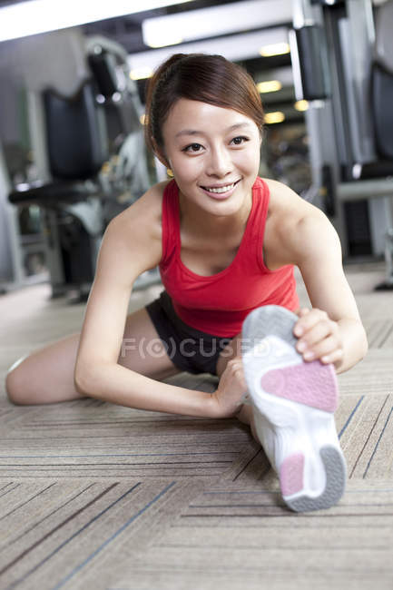 Chinese woman stretching at gym — Stock Photo