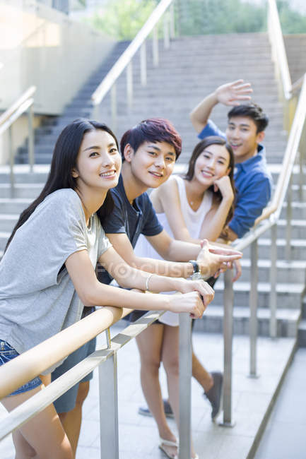 Chinese friends leaning on balustrade and posing on street — Stock Photo