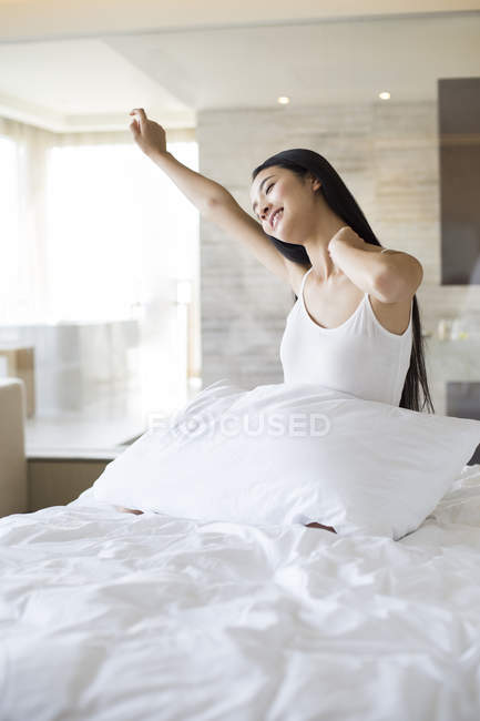 Chinesin dehnt sich morgens mit geschlossenen Augen im Bett — Stockfoto