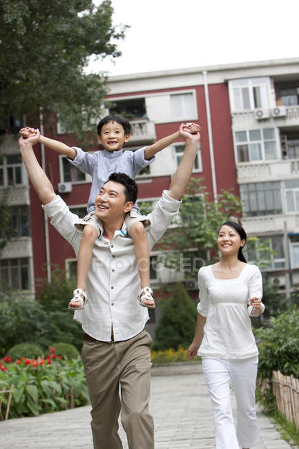 Китайский отец носит сына на плечах в саду — стоковое фото