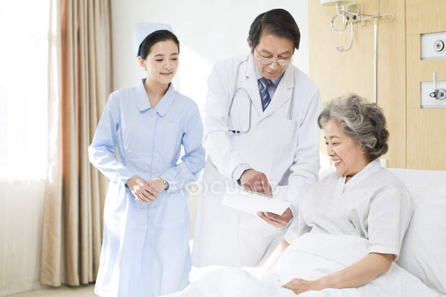 Chinese medical workers talking with patient in hospital — Stock Photo