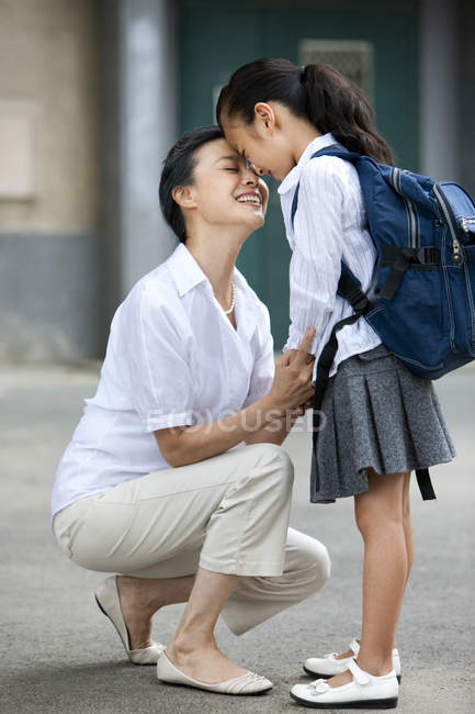 Chinese schoolgirl standing face to face with grandmother — Stock Photo