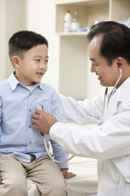 Китайский взрослый врач осматривает мальчика в больнице — стоковое фото