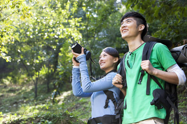Amici cinesi con fotocamera digitale in escursione nella foresta — Foto stock