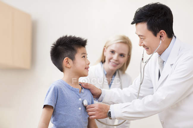Лікарі вивчають хлопчика зі стетоскопом — стокове фото