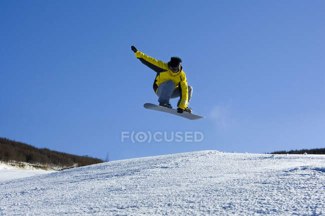 Молодой китаец катается на сноуборде на лыжном курорте — стоковое фото