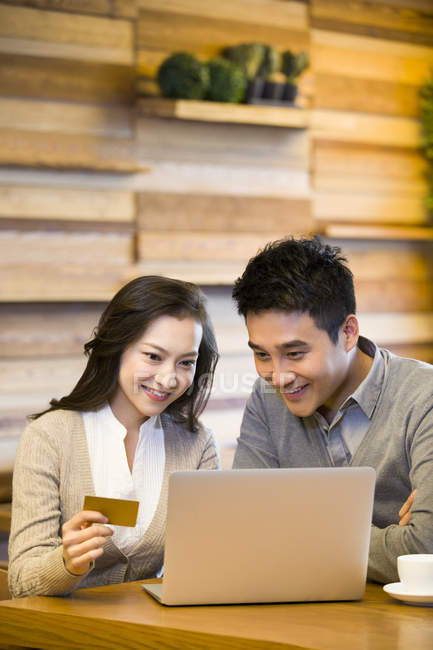 Chinese couple shopping online in cafe — Stock Photo