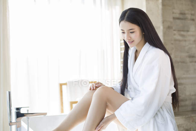 Chinese woman sitting on bathtub and looking down — Stock Photo